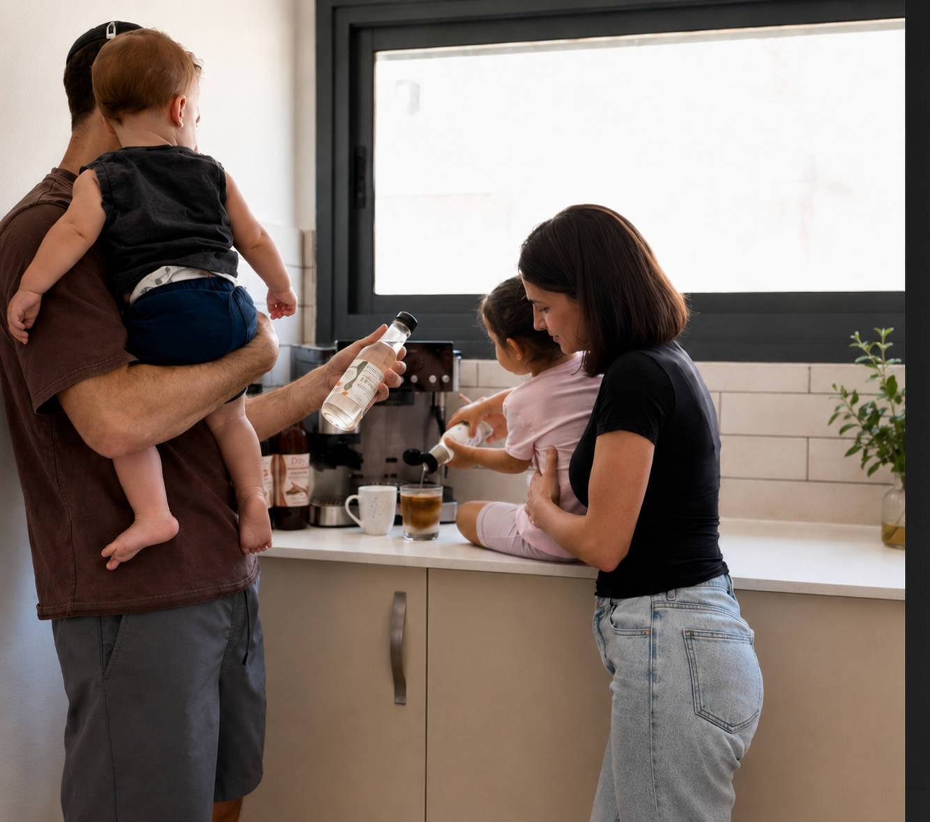 Isaac and Niki with their kids in the kitchen, pouring Drizzl syrup